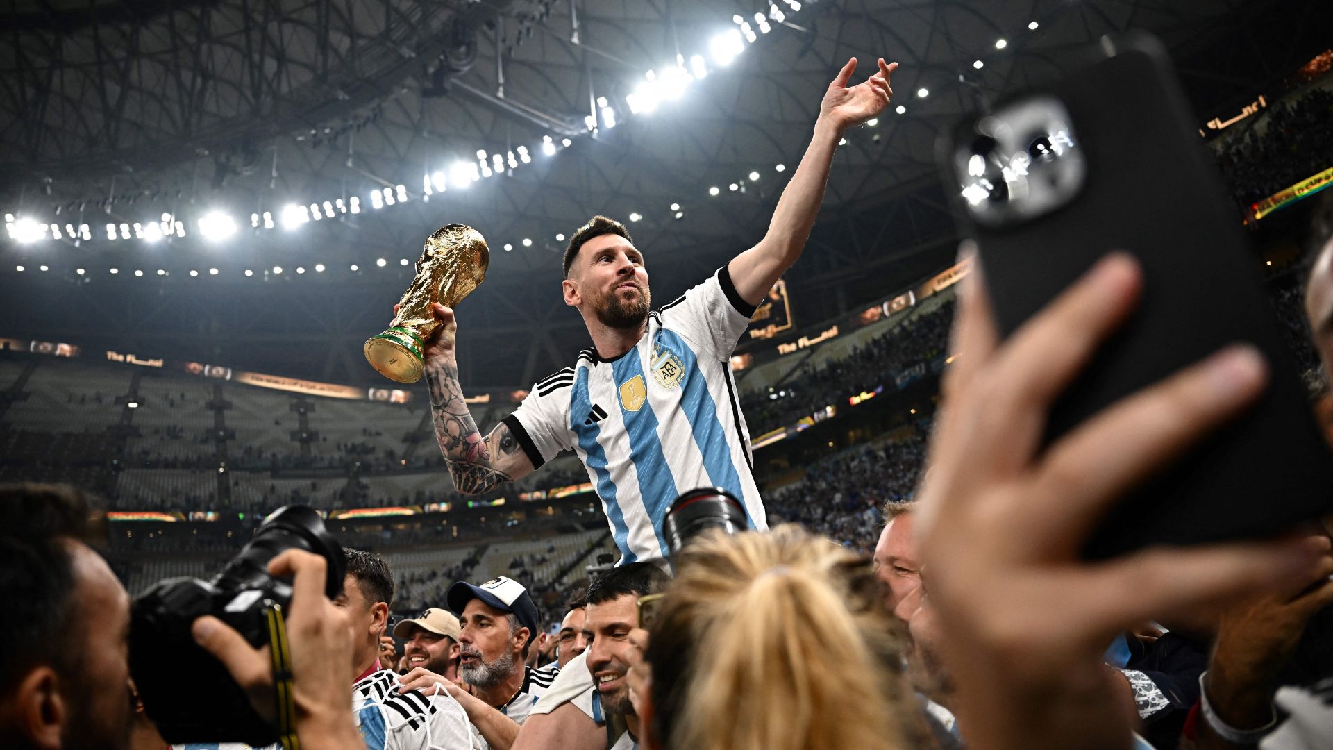 Lionel Messi (R) holds the FIFA World Cup Trophy following the trophy ceremony after Argentina won the Qatar 2022 World Cup