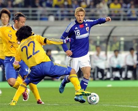 كيسوكي هوندا يحاول تجاوز المدافع يوجي ناكازاوا