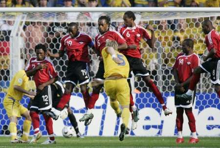 السويدي أريك إدمان (5) ينفذ ضربة حرة مباشرة والدفاع التريندادى مستميت 