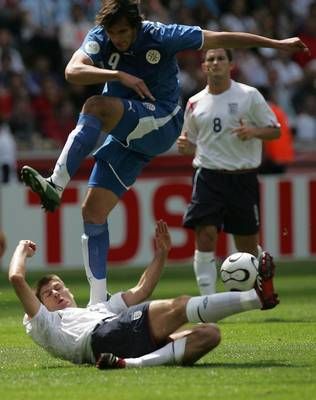 روكي سانتا كروز مهاجم الباراغواي في مضايقة مع ستيفين جيرارد الانجليزي