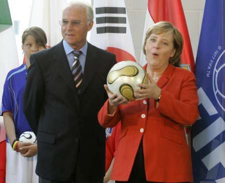 المستشارة الالمانية ميركيل (يمين) تتسلم كرة المباراة النهائية 