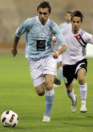 احمد هايل لاعب للفيصلي يسير بالكرة وسط مطاردة مدافع المنشية