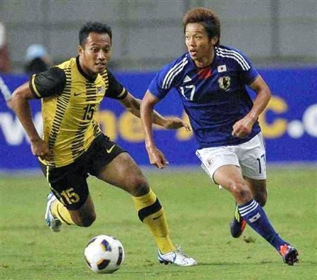 لاعب الوسط الياباني هيروشي كيوتاكي يخترق الدفاع الماليزي