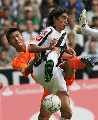 لاعب منسن جلادباخ زي انتونيو (اليمين) ولاعب كونبوي جيايي شاو يتسابقان للحصول على الكرة