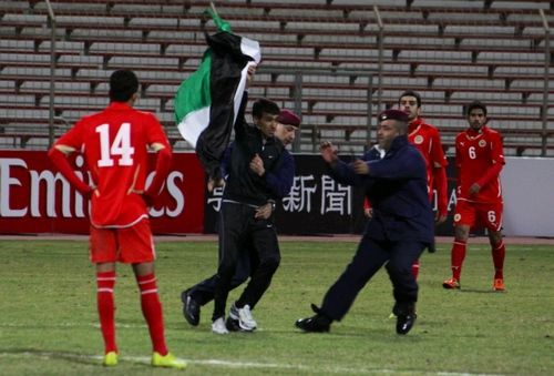 احد الجماهير يقتحم ملعب لقاء الأولمبي البحريني ونظيره السوري حاملا علم ما يسمى بالثورة السورية