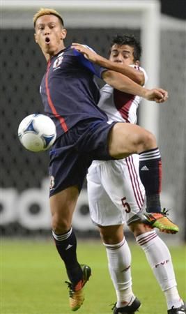 كيسوكي هوندا في صراع كروي مع أحد لاعبي منتخب فنزويلا