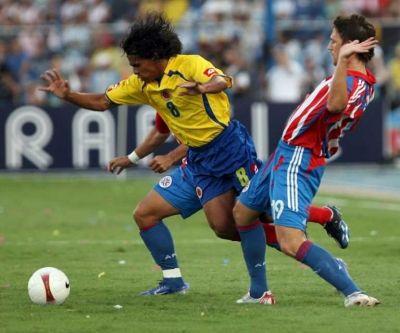 دافيد فيريرا لاعب المنتخب الكولومبي يحاول المرور بين لاعبين من منتخب البرغواي