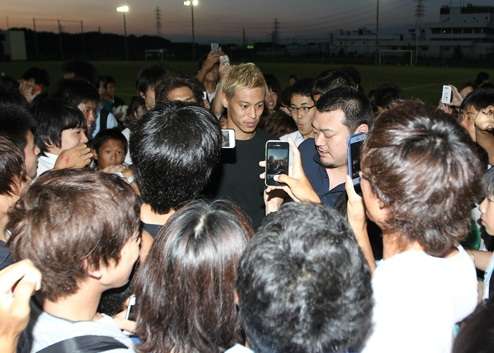 كيسوكي هوندا محاط بالمشجعين عند زيارته للمدرسة الكروية