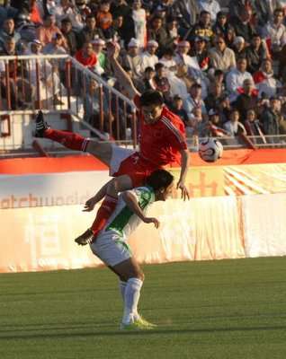 مدافع منتب الصين يقفز فوق المهاجم العراقي مصطفى كريم