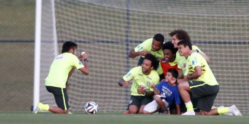 نيمار يقوم بتصوير الطفل مع اللاعبين خلال مران البرازيل