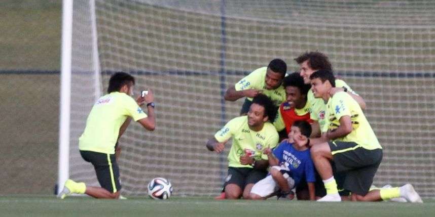 نيمار يقوم بتصوير الطفل مع اللاعبين خلال مران البرازيل