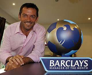 فيـل بـراون وأمامه جائـزة أفضل مـدرب