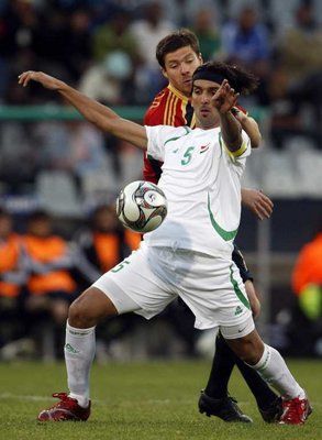 كابتن منتخب العراق نشأت أكرم يسيطر على الكرة من امام الاسباني تشافي الونسو