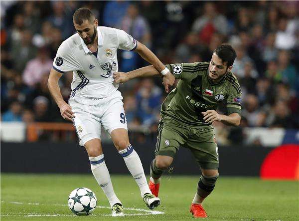 كريم بنزيمة في صراع على الكرة مع لاعب وارسو