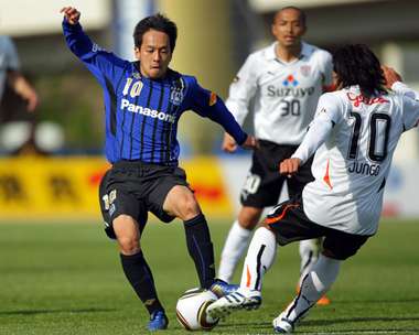 لاعب الوسط فوتاغاوا يحاول تجاوز مدافعي شيميزو في مباراة جامبا وشيميزو