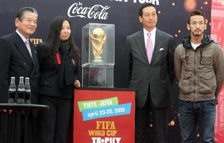 أسطورة الكرة اليابانية السيد هيديتوشي ناكاتا ( يمين ) يقف بجانب كأس العالم في طوكيو