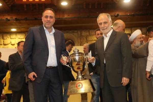 فنيش مع رئيس نادي العهد تميم سليمان وبينهما كأس الدوري خلال حفل الاستقبال.